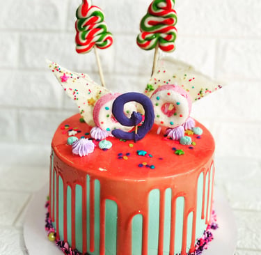 Colorful 9th birthday drip cake with pink glaze, lollipops, donuts, and sprinkles.