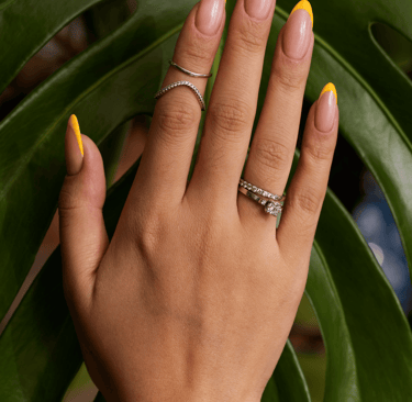 la main d'une femme avec des bagues et du vernis sur les ongles