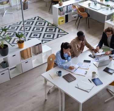 Tres personas sentadas en una mesa y trabajando en la oficina.