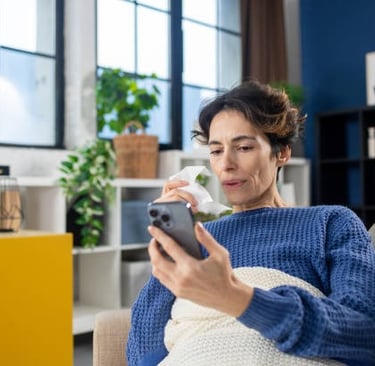 Mujer mirando su teléfono, sosteniendo un pañuelo