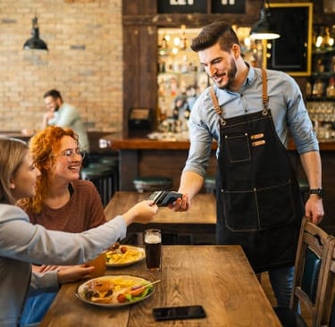 Dos mujeres pagando con tarjeta en un restaurante