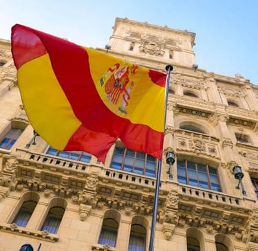 Bandera española delante de un gran edificio amarillo