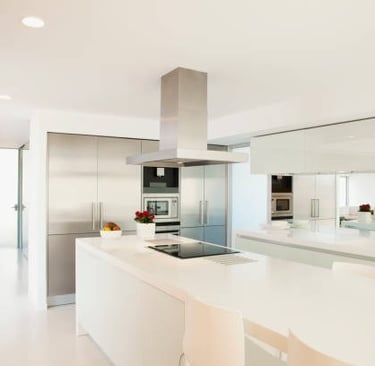 Cocina con muebles blancos, un ramo de rosas y un bol de fruta en la encimera.