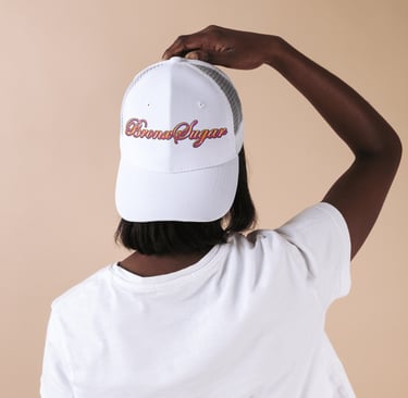 A person from behind wearing a white Bronx Sugar trucker hat and a matching t-shirt.