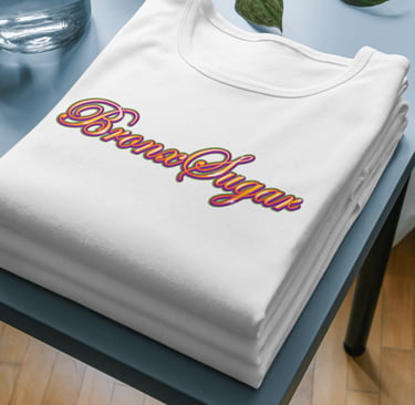 Folded white t-shirt featuring a colorful retro Bronx Sugar script logo on a blue side table.