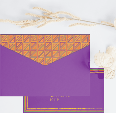 Purple stationery envelope with orange geometric pattern and dried floral accents on white background.