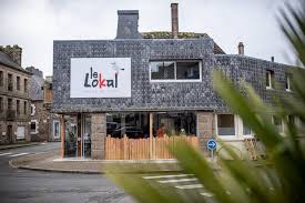 Exterior view of Le Lokal restaurant in Belle-Isle-en-Terre, Brittany, France, featuring a modern gr