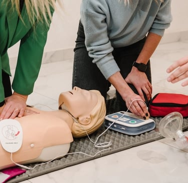 Two women administering CPR training on a CPR dummy in a training