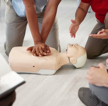A traininer training student on administering CPR on a dummy, with other students taking notes