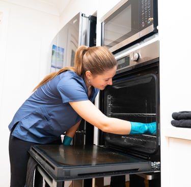 a woman in a blue shirt is cleaning a oven