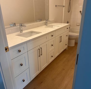 Modern bathroom with double-sink white shaker vanity, quartz countertop, and wood-look flooring — RT