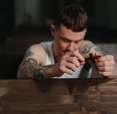 a man with tattoos on his arm and a cigar