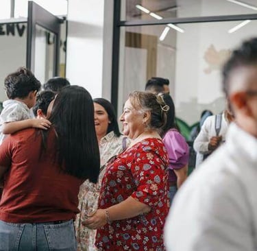 People embracing and smiling during a warm indoor social or family gathering.