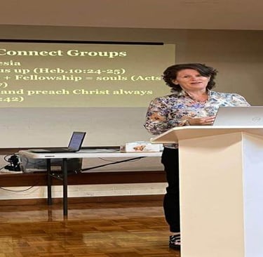 Elisha presents at a podium with a slide behind her about connect groups, fellowship, and living out