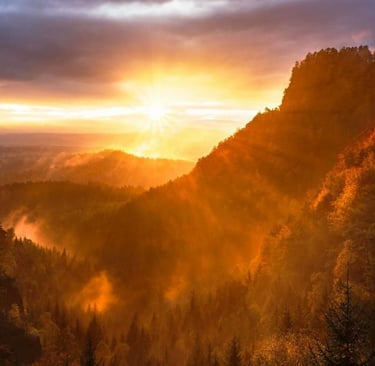 a sunset over a mountain range with a view of the sun setting