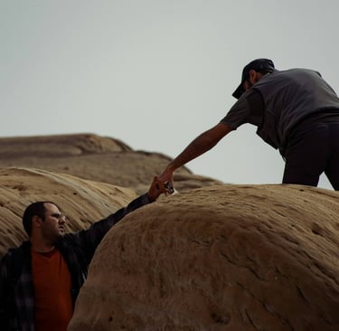 a man and a woman holding hands on a rock formation