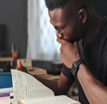 A man sitting at a desk with a bible and a laptop