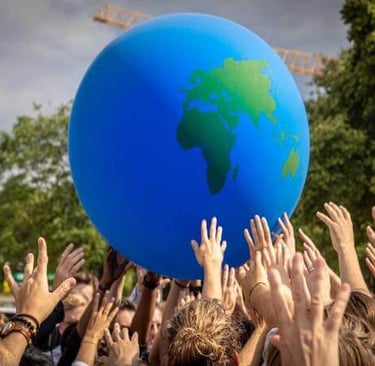 Group of people lifting a globe together, symbolizing unity and global care.