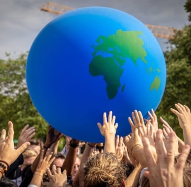 a group of people holding hands up to a blue ball