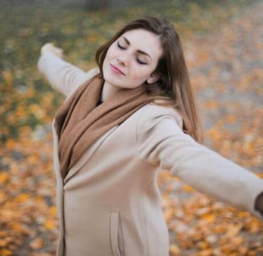 Woman standing with arms open outdoors, expressing freedom, peace, and gratitude.