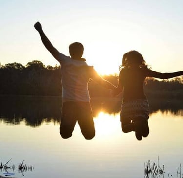 two people jumping in the air with their hands up