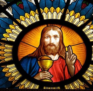 Stained glass window showing Jesus with a chalice and blessing gesture, surrounded by vibrant symbol