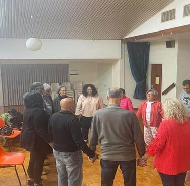 Church members standing in a circle holding hands in prayer during a small group meeting.