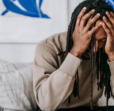 a man with dreadlocks sitting on a couch with his hands on his head
