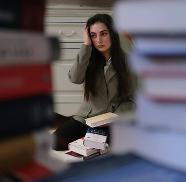 a woman sitting on a desk with books and a laptop