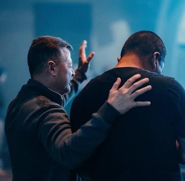 two men standing in a room with a praying 