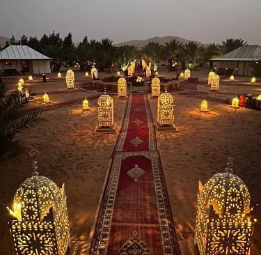 a long red carpet in desert with lamps around