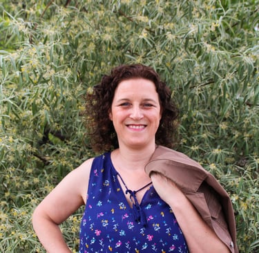 Natanya in a blue top with a brown jacket