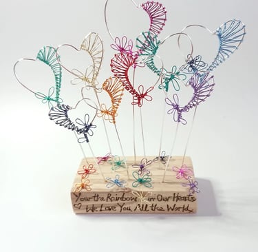 Cozams quirky hearts, seven in coloirs of the rainbow in wood reflecting flowers in garden
