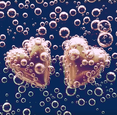 zwei metallene Herzen schwimmen im Wasser und sind von Blasen umgeben