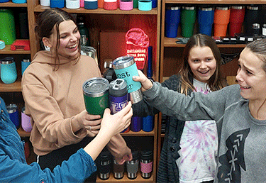 a group of people standing around a table holding tumblers