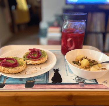 DIY pickled onions and plant-based pesto on a bagel, DIY plant-based yogurt, pineapple, pistachios