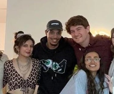 A diverse group of smiling young friends posing together for a group photo indoors.