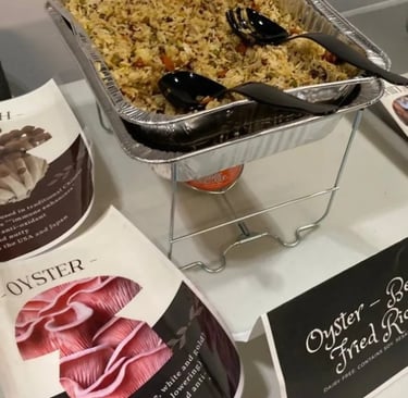 A buffet tray of oyster mushroom fried rice served with black serving spoons at a catered event.