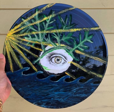 Hand-painted vinyl record art featuring an eye, green leaves, ocean waves, and gold glitter sun rays.