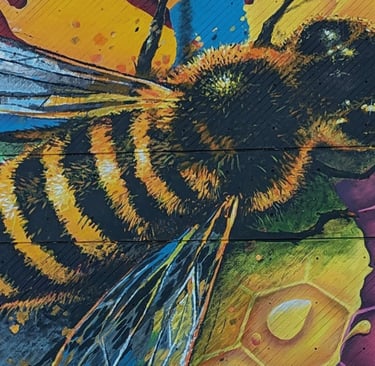 Vibrant honey bee mural painted on wood featuring a honeycomb pattern and colorful street art.
