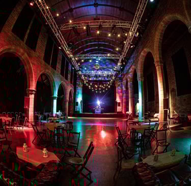 The interior of the Roxy Central, an open space with vaults, red lighting and scattered tables.