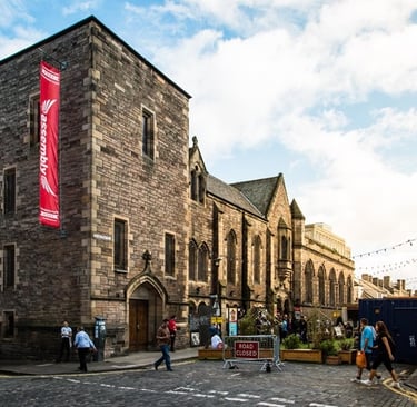 The exterior of the Assembly Roxy Central, a 19c stone building with a 3-story tower.