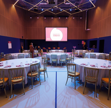 The Social Hub theater set up with round tables and a screen