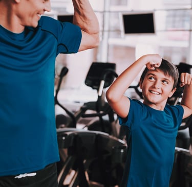 Un adulto e un bambino in palestra che mostrano i muscoli in modo giocoso, creando un momento divertente e motivante durante 