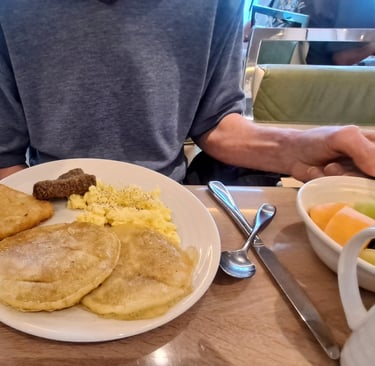 A plate of breakfast foods, potato patty, eggs, pancakes