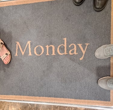 Three feet on a rug that says "Monday"