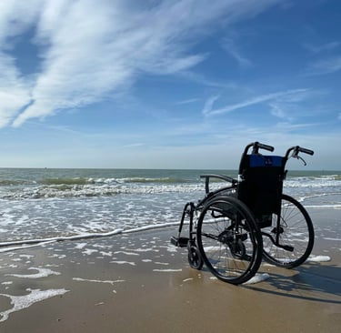 Wheelchair at edge of water on beach. Photo credit - Photo by //unsplash.com/@hansmoe