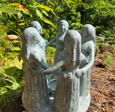 a statue of a group of women around a tree stump