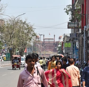 Crowded street in Old Delhi leading towards the historic Red Fort monument under a clear sky.