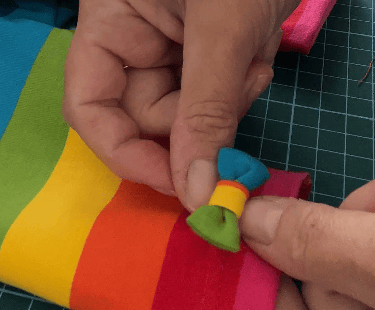 a person is making a rainbow - coloured bow to attach to leggings